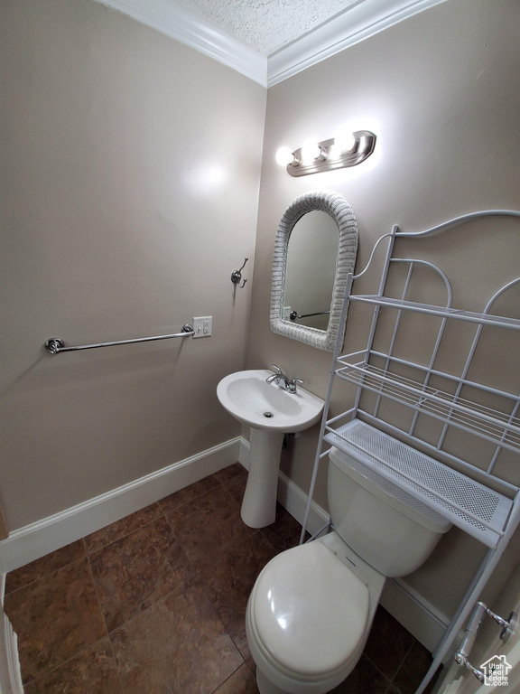 Half bathroom with toilet, baseboards, ornamental molding, and a textured ceiling