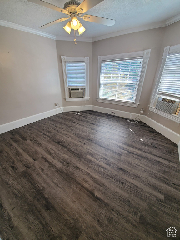 Spare room with dark wood-type flooring, cooling unit, ornamental molding, a ceiling fan, and baseboards