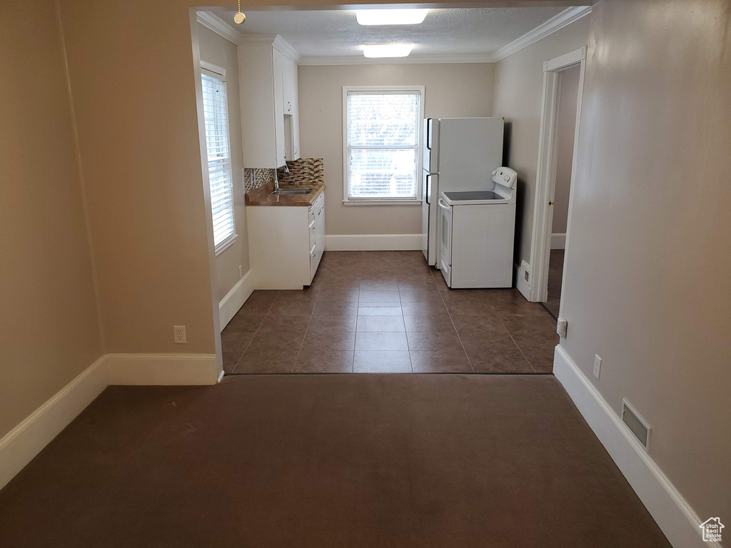 Laundry area featuring ornamental molding, baseboards, dark tile patterned flooring, and dark carpet