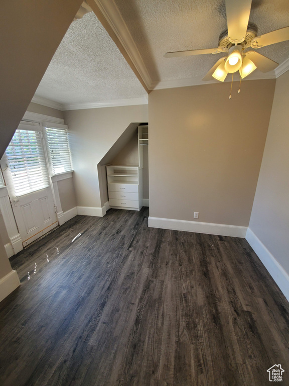 Bonus room with a textured ceiling, dark wood-type flooring, a ceiling fan, and baseboards