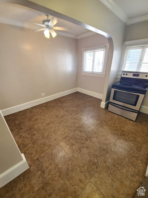 Unfurnished living room featuring ornamental molding, arched walkways, ceiling fan, and baseboards
