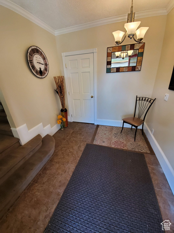 Tiled foyer featuring ornamental molding, a chandelier, and baseboards