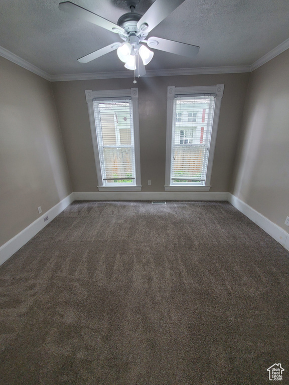 Unfurnished room featuring healthy amount of natural light, carpet, ornamental molding, baseboards, and a ceiling fan