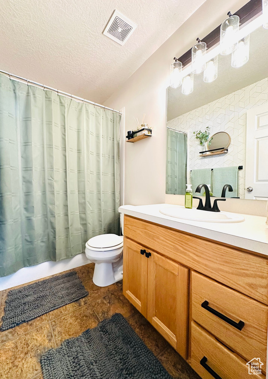 Full bathroom with toilet, vanity, a textured ceiling, and a shower with curtain