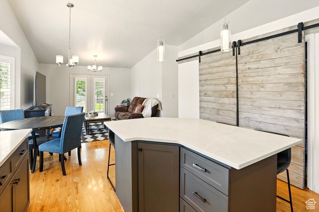 Kitchen with vaulted ceiling, a barn door, a kitchen bar, gray cabinetry, and open floor plan