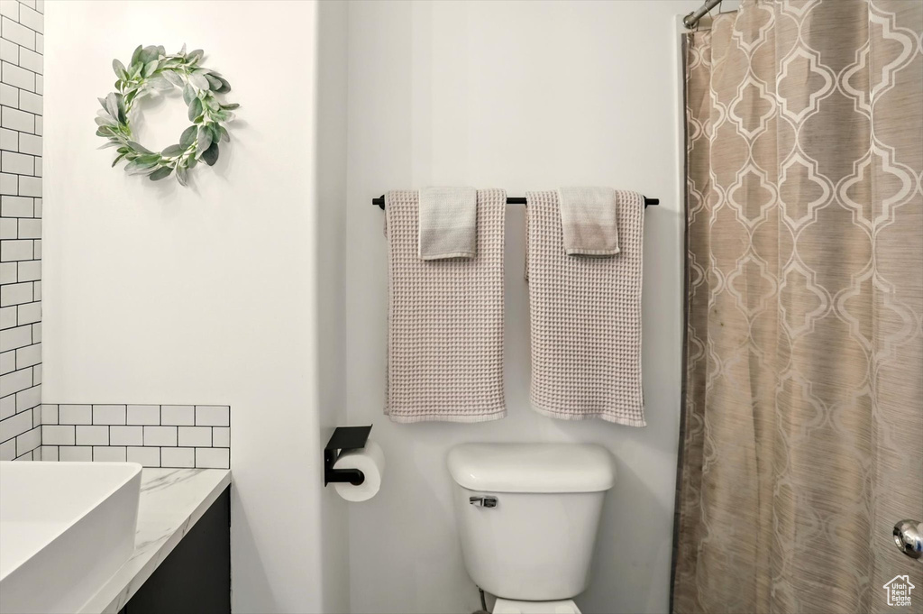 Bathroom featuring toilet, vanity, and a shower with curtain