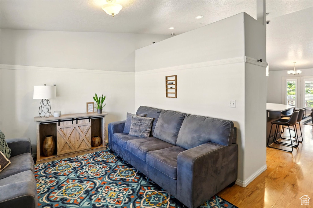 Living room with light wood-style floors, a chandelier, baseboards, and a textured ceiling