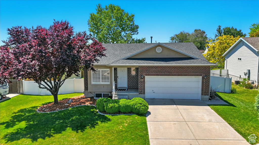 View of front facade with a shingled roof, a garage, concrete driveway, and brick siding