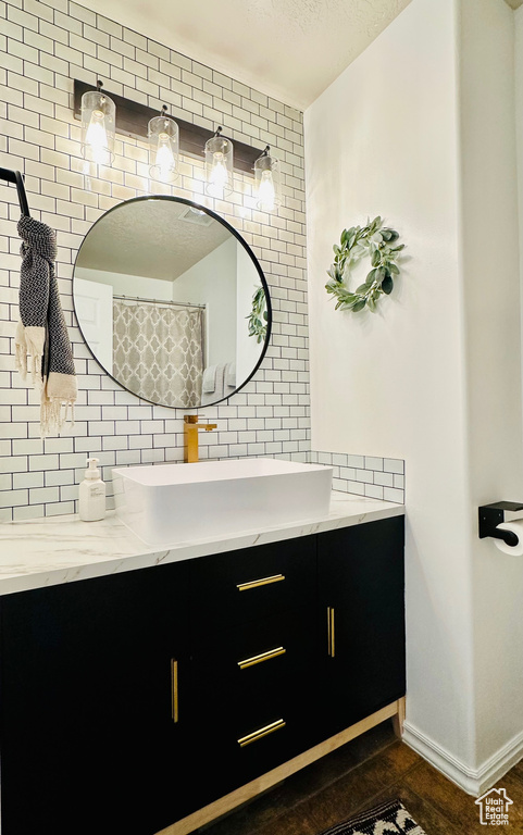 Bathroom with vanity, backsplash, a textured ceiling, and baseboards