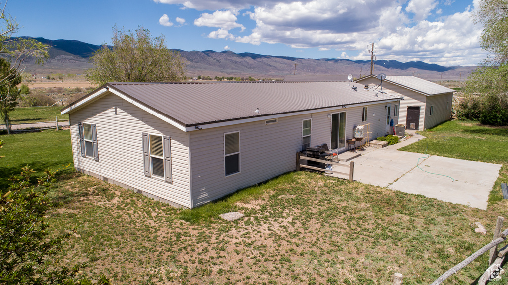 Rear view of house with a patio, a mountain view, a lawn, and metal roof