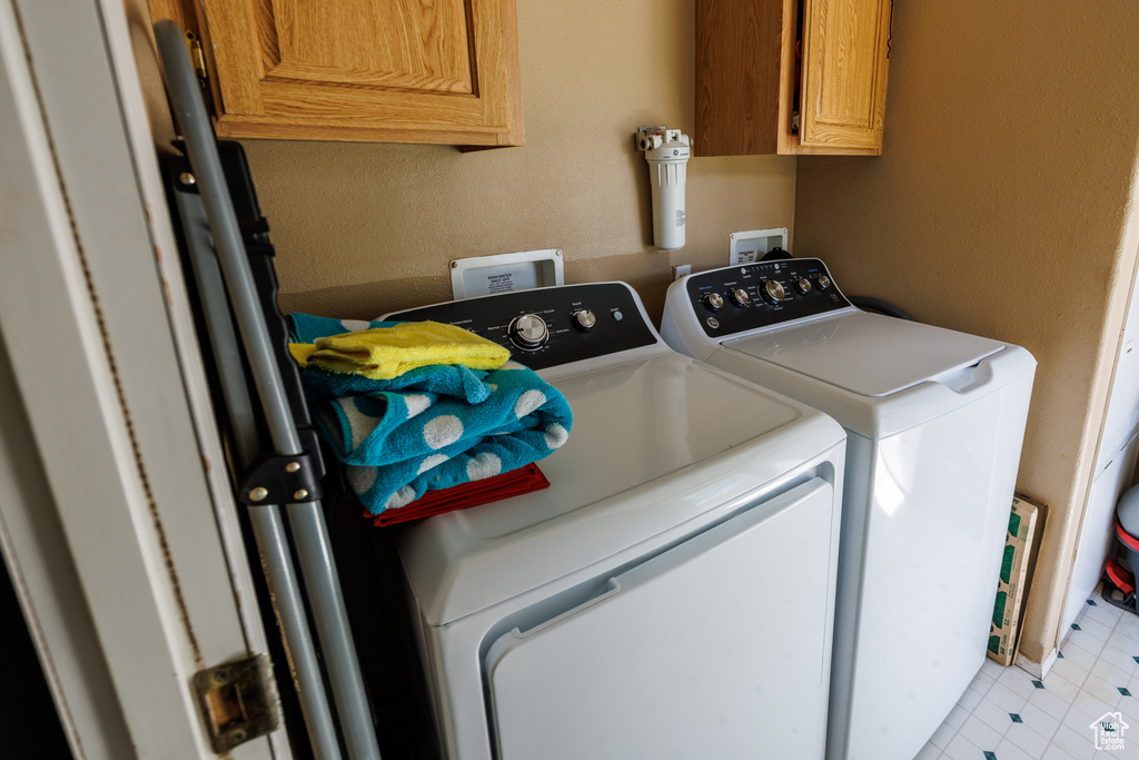 Clothes washing area featuring washing machine and clothes dryer and cabinet space