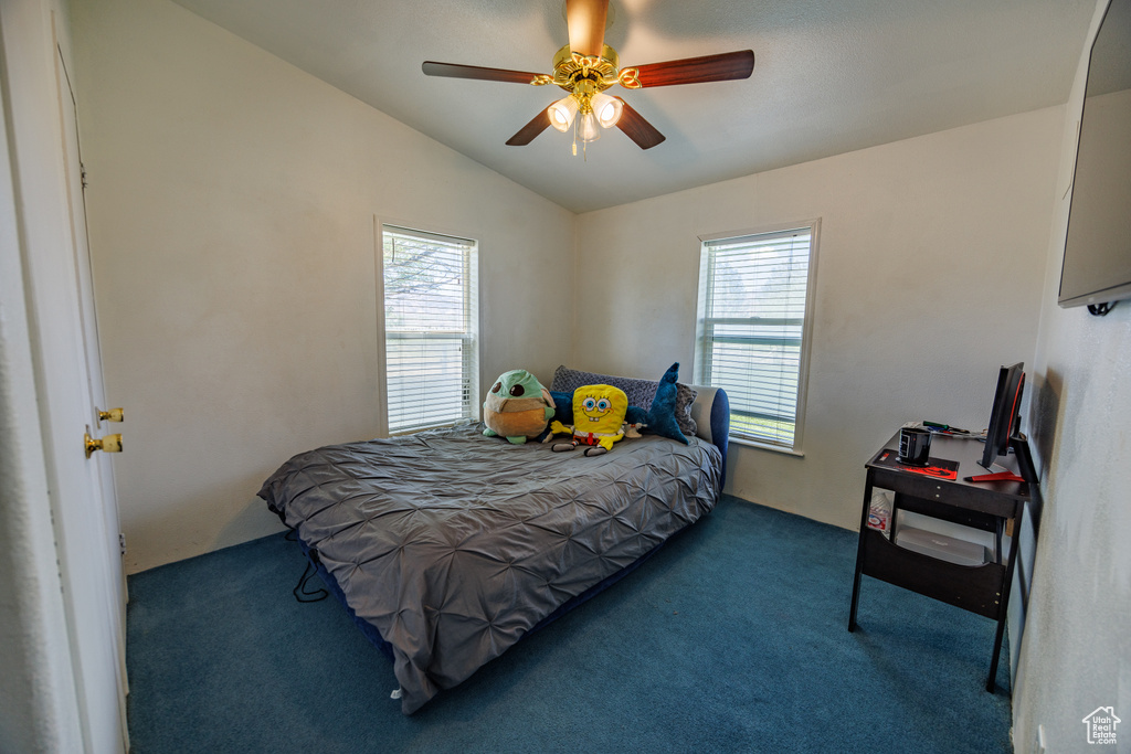 Bedroom with carpet floors, multiple windows, vaulted ceiling, and a ceiling fan