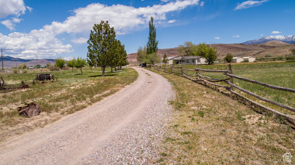 View of dirt / gravel road with a rural view and a mountain view