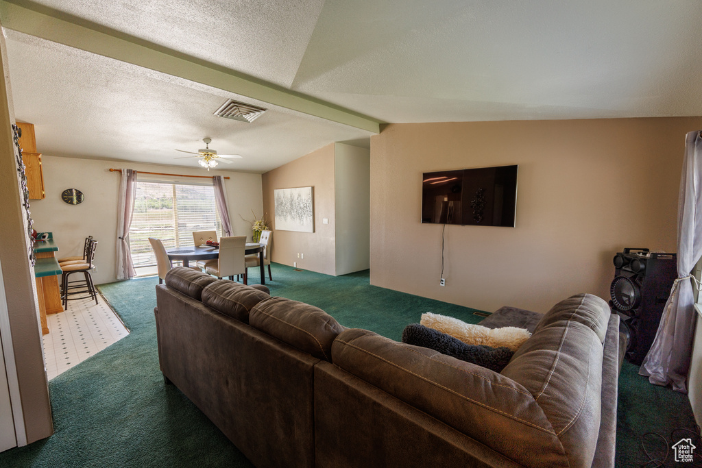 Living area with dark colored carpet, a ceiling fan, and lofted ceiling