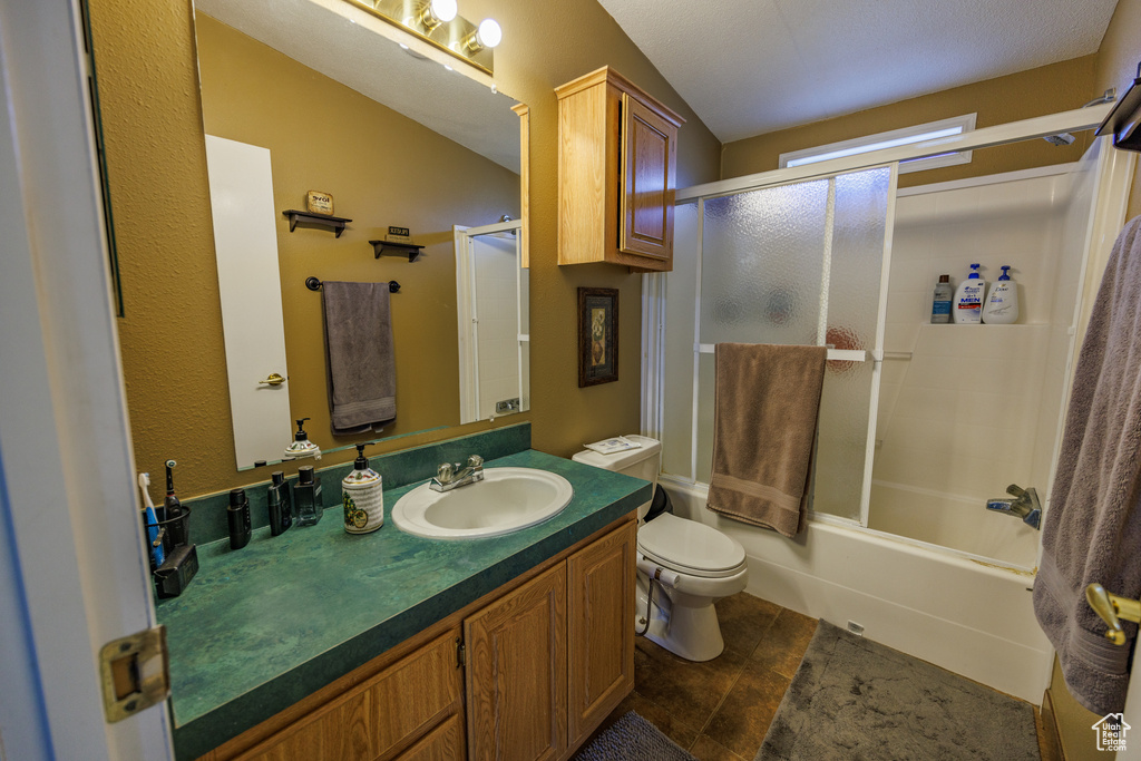 Bathroom featuring toilet, vanity, combined bath / shower with glass door, and tile patterned floors