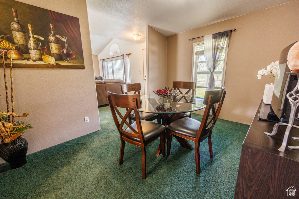 Dining area with dark carpet and vaulted ceiling