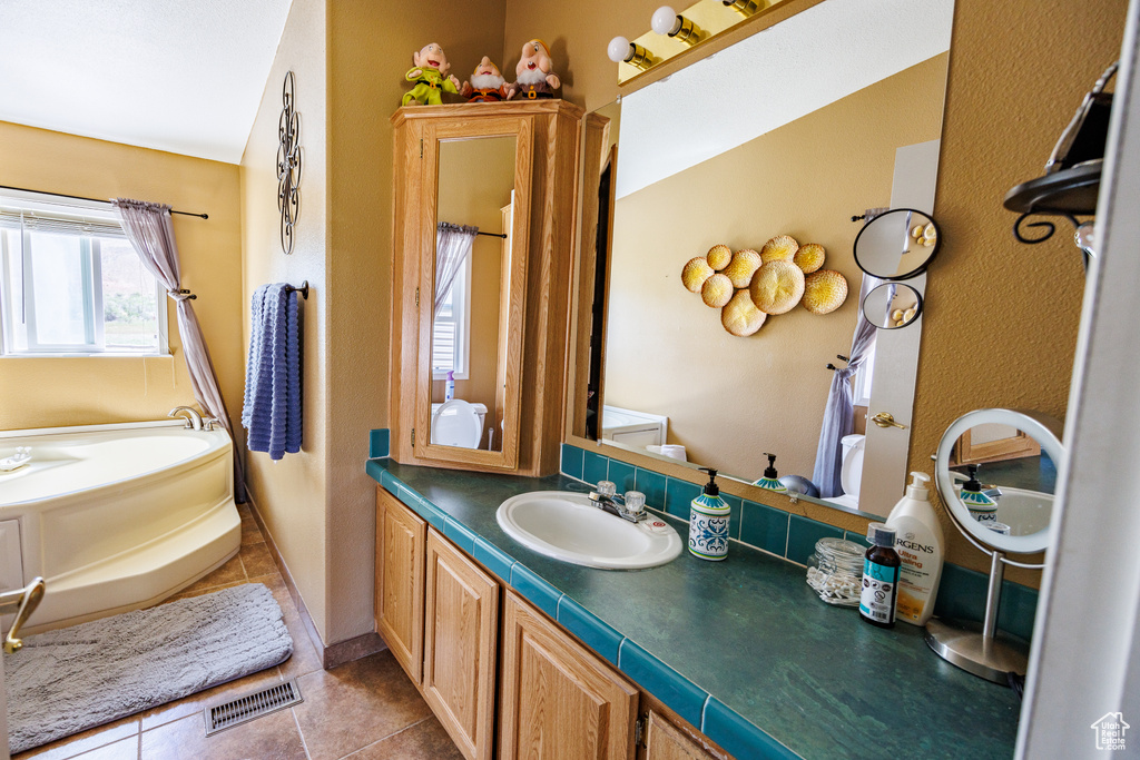 Full bathroom with tile patterned floors, a garden tub, and vanity