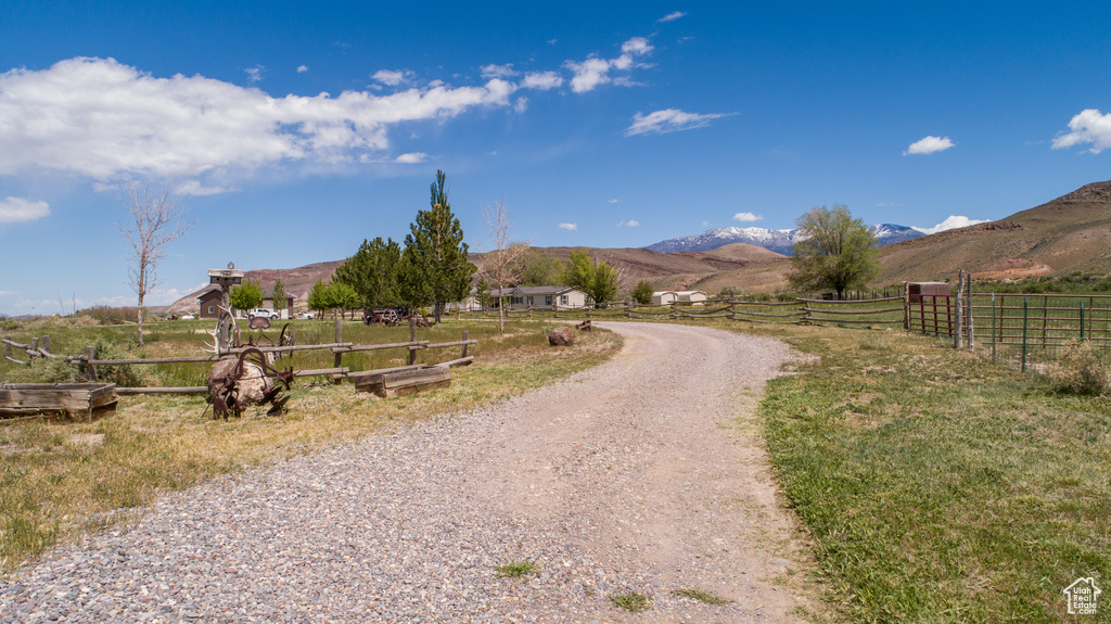 View of dirt / gravel road with a view of rural / pastoral area and a mountain view