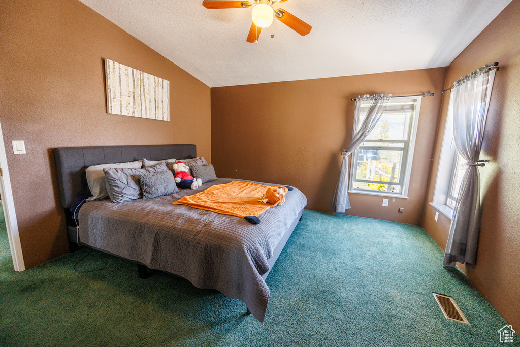 Carpeted bedroom featuring lofted ceiling and a ceiling fan