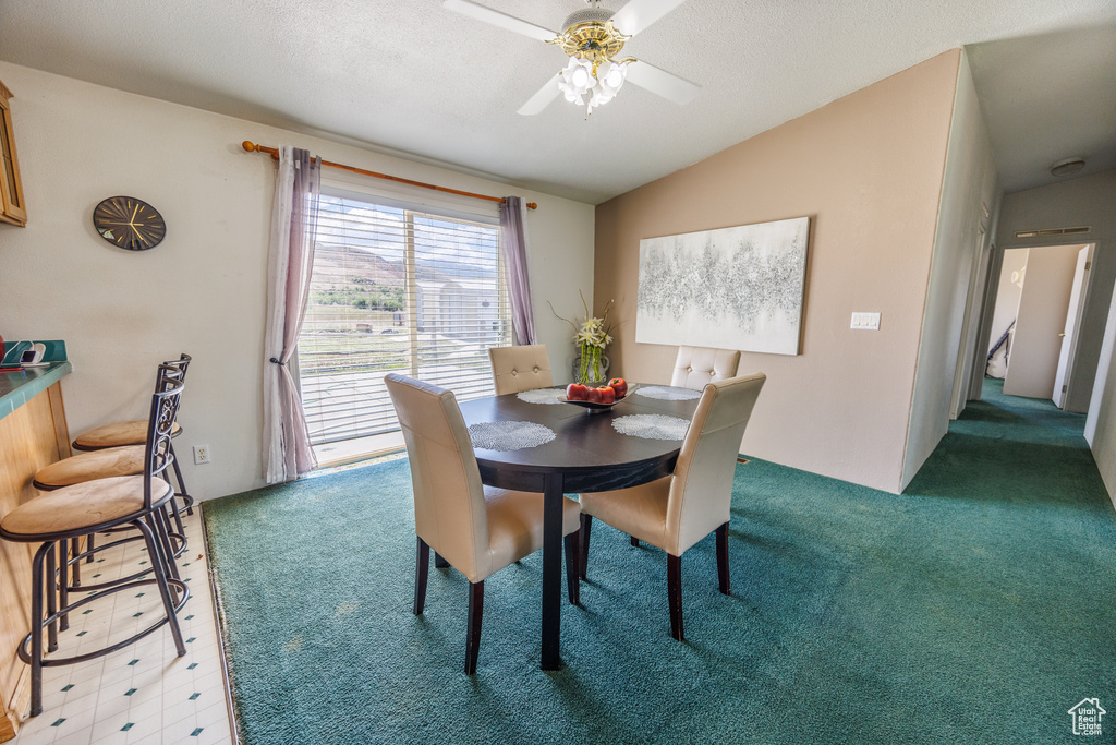 Dining room featuring vaulted ceiling, light carpet, and a ceiling fan
