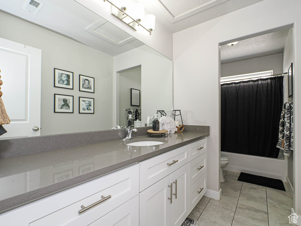 Full bath featuring toilet, vanity, tile patterned flooring, and shower / bath combo with shower curtain