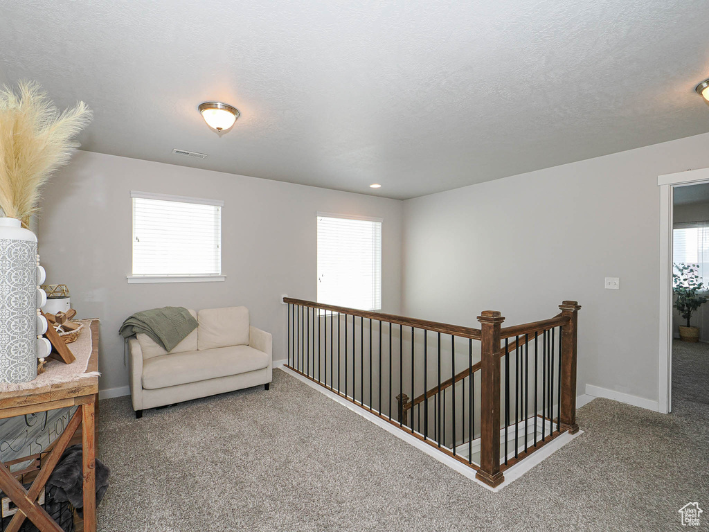Living area with carpet, an upstairs landing, plenty of natural light, and baseboards