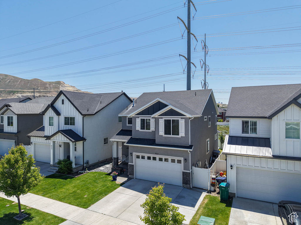 Modern farmhouse style home featuring a garage, concrete driveway, board and batten siding, a front yard, and a residential view