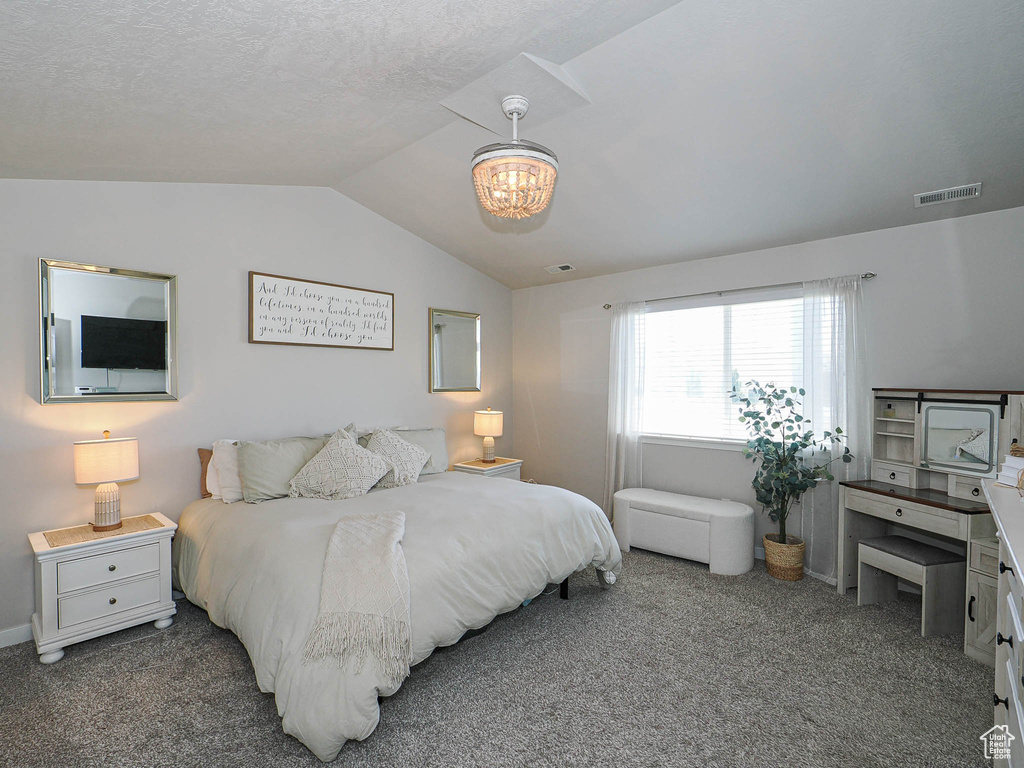 Bedroom featuring lofted ceiling, a chandelier, and carpet