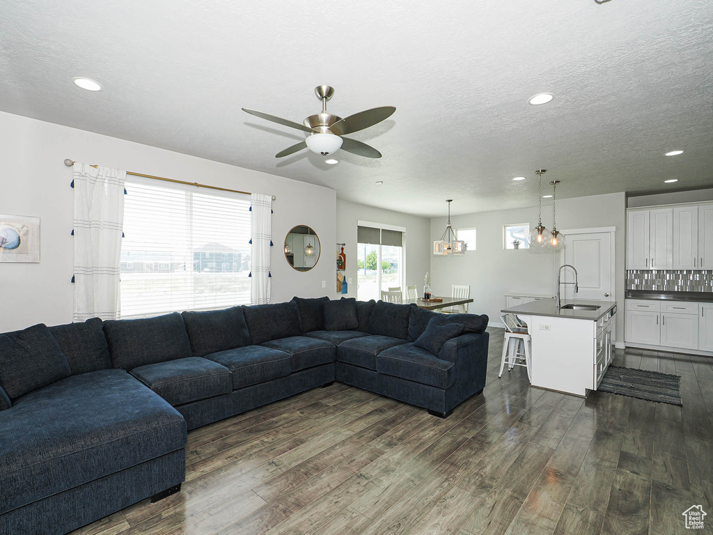 Living room featuring dark wood finished floors, a ceiling fan, recessed lighting, and a textured ceiling