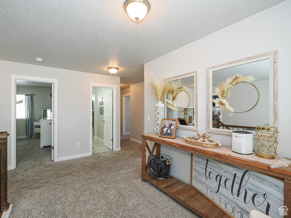 Hall with carpet floors, a textured ceiling, and baseboards