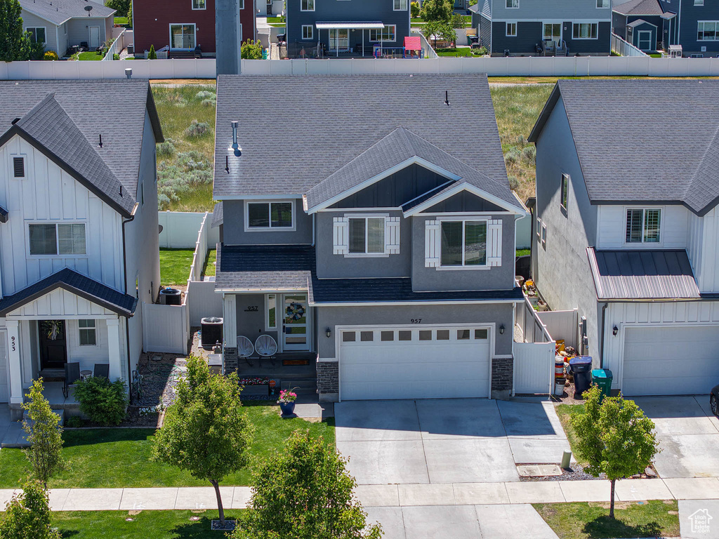 View of front facade featuring a residential view, roof with shingles, a garage, driveway, and stone siding