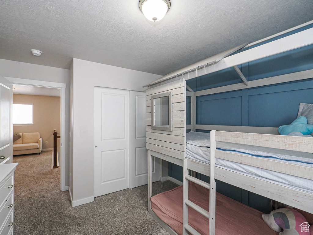 Carpeted bedroom featuring a textured ceiling, a closet, and baseboards