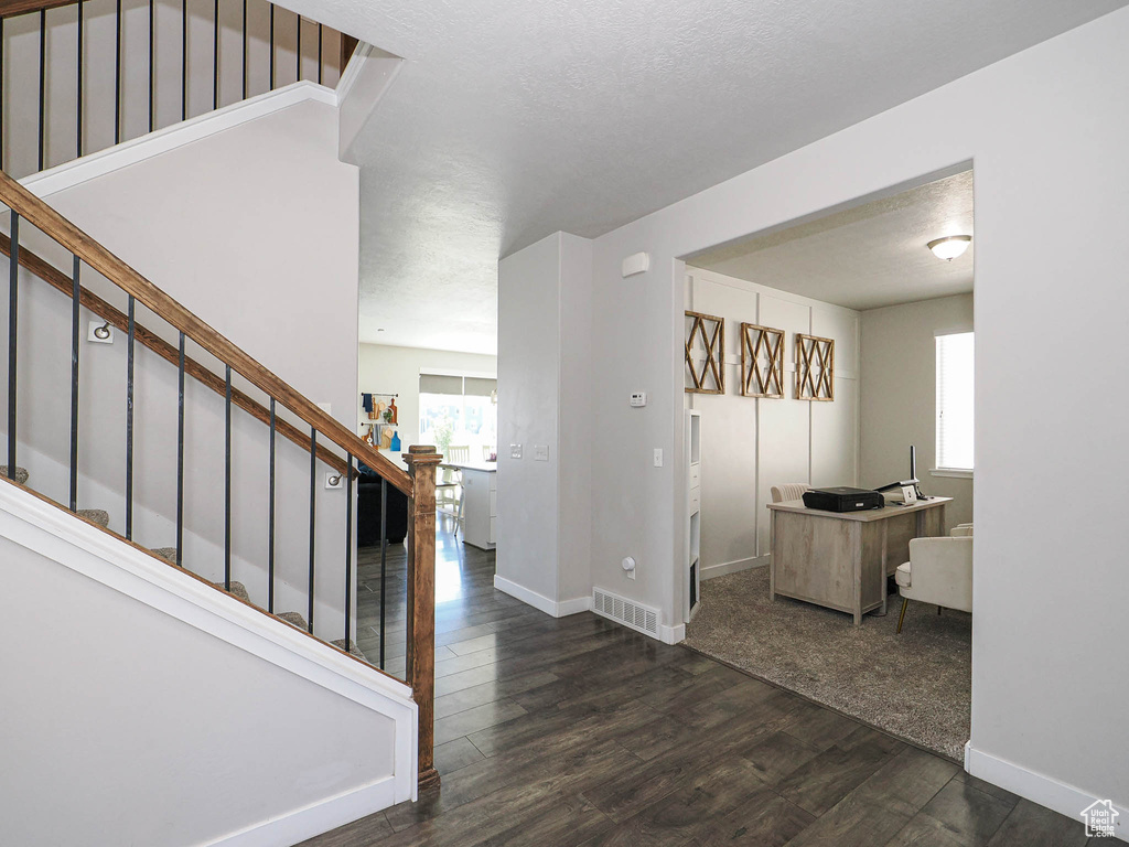 Entryway featuring dark wood-type flooring, baseboards, and stairway
