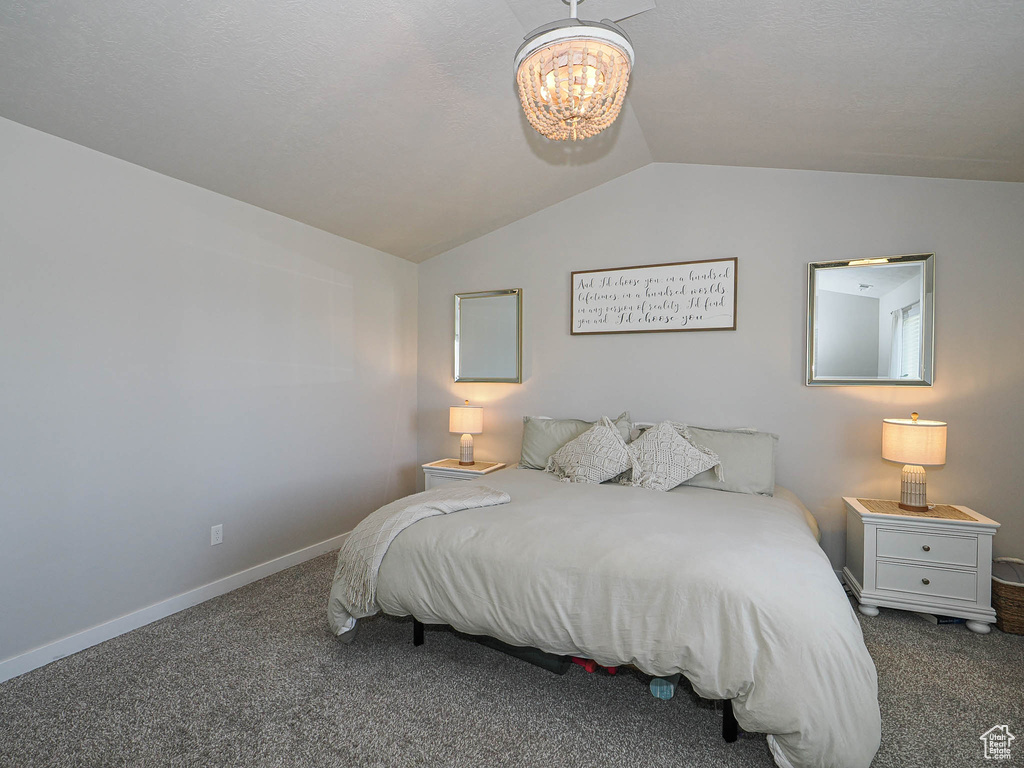Carpeted bedroom featuring lofted ceiling, a chandelier, and baseboards