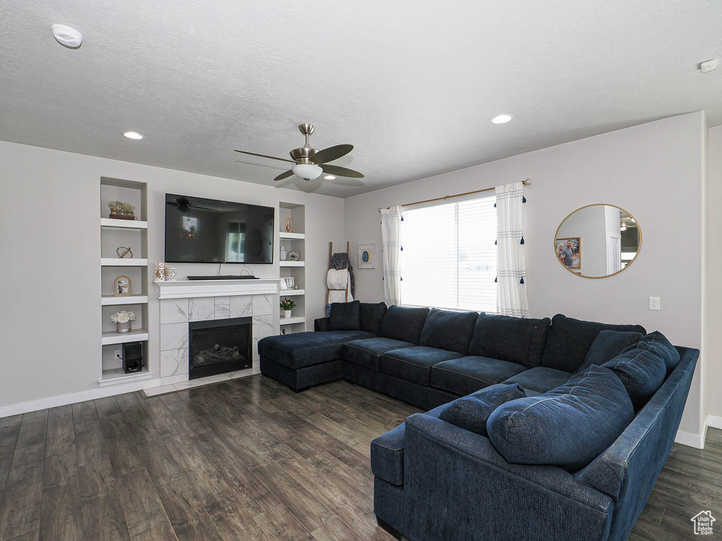 Living area with ceiling fan, dark wood-type flooring, baseboards, a premium fireplace, and recessed lighting