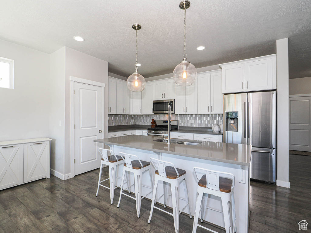 Kitchen featuring appliances with stainless steel finishes, tasteful backsplash, baseboards, white cabinetry, and dark wood-style floors