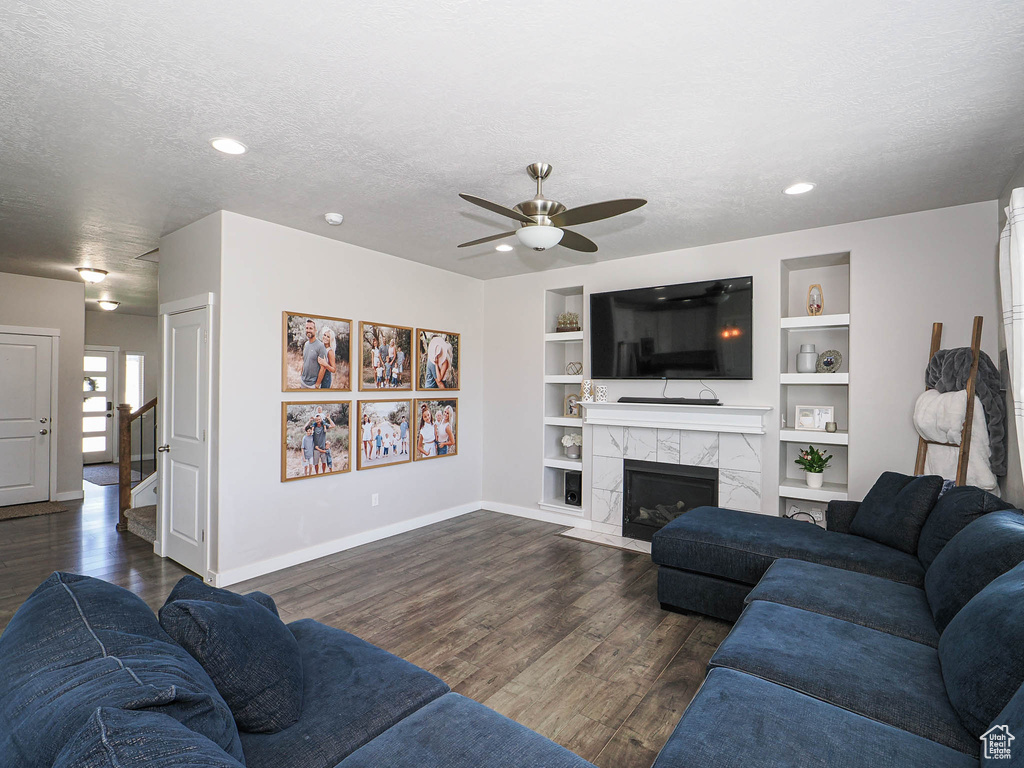 Living room with baseboards, ceiling fan, dark wood-style floors, a textured ceiling, and built in features