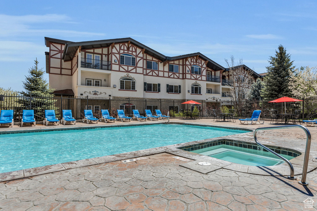 Community pool featuring an in-ground hot tub and a patio