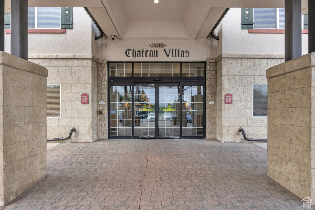 View of exterior entry featuring stone siding, stucco siding, and a security system