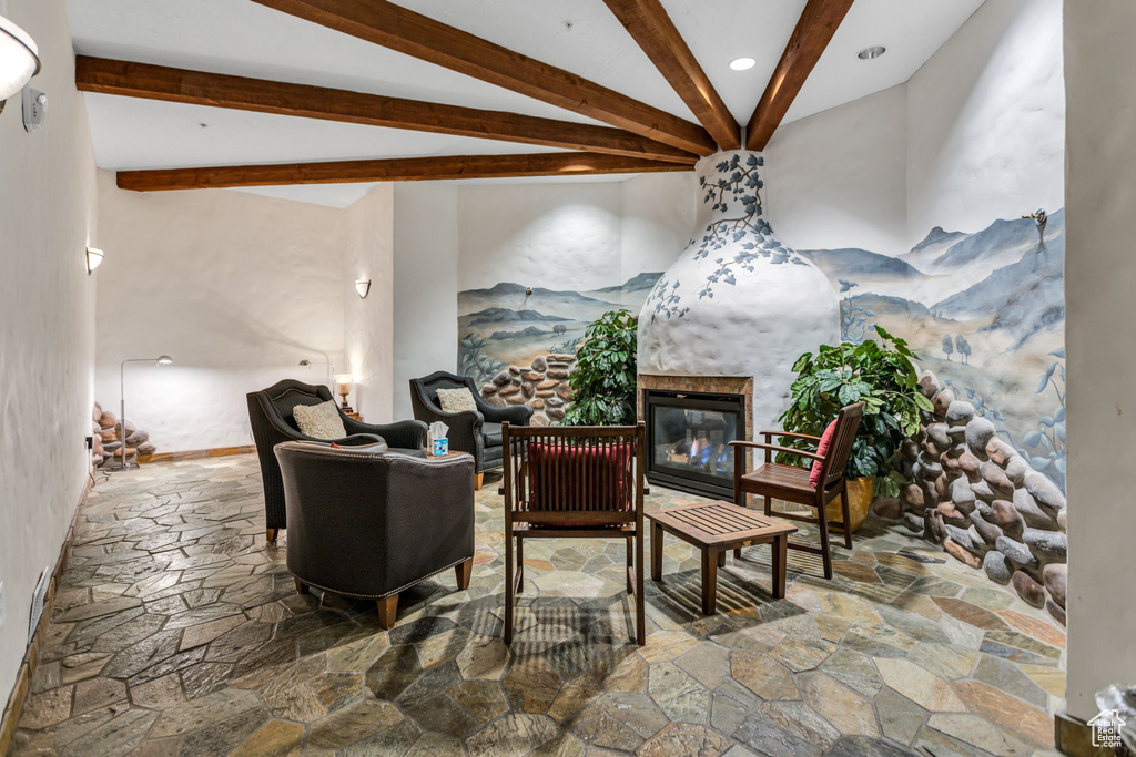Living room with stone floors, beam ceiling, a glass covered fireplace, and recessed lighting