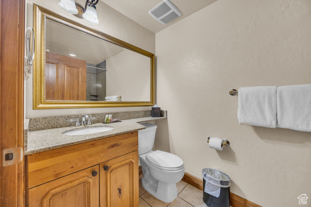 Full bath with tile patterned floors, baseboards, vanity, toilet, and a shower