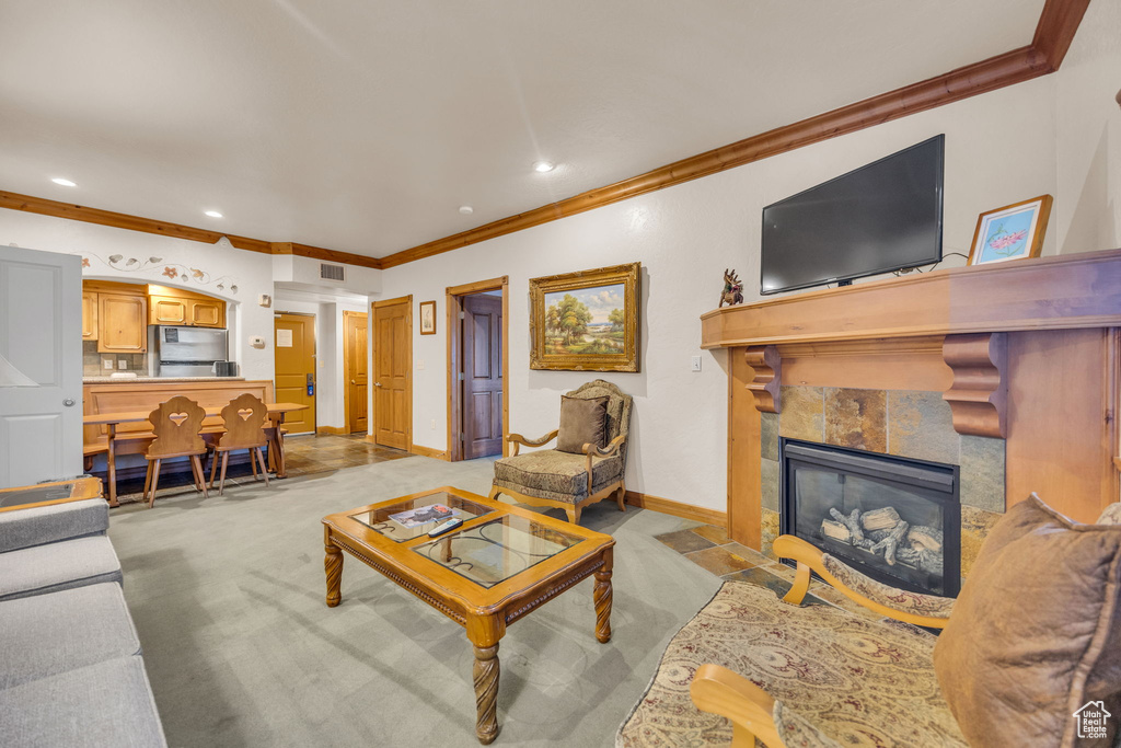 Living room featuring light carpet, ornamental molding, baseboards, recessed lighting, and a tile fireplace