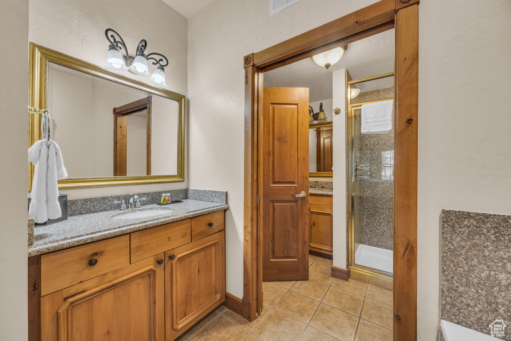 Bathroom featuring a stall shower, vanity, tile patterned flooring, and a textured wall