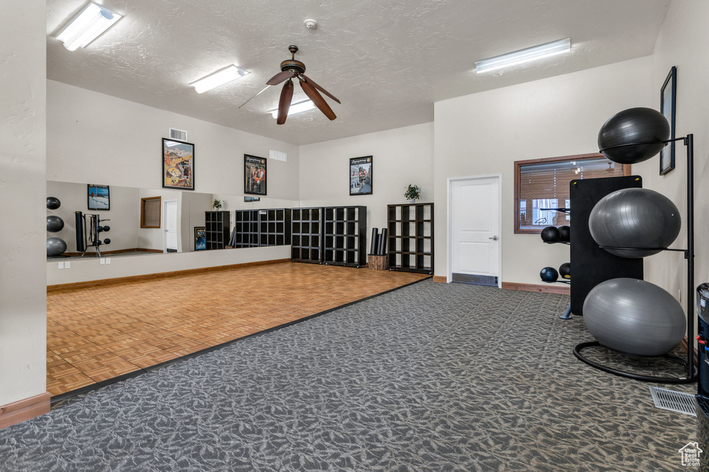 Workout room with ceiling fan, a textured ceiling, and baseboards