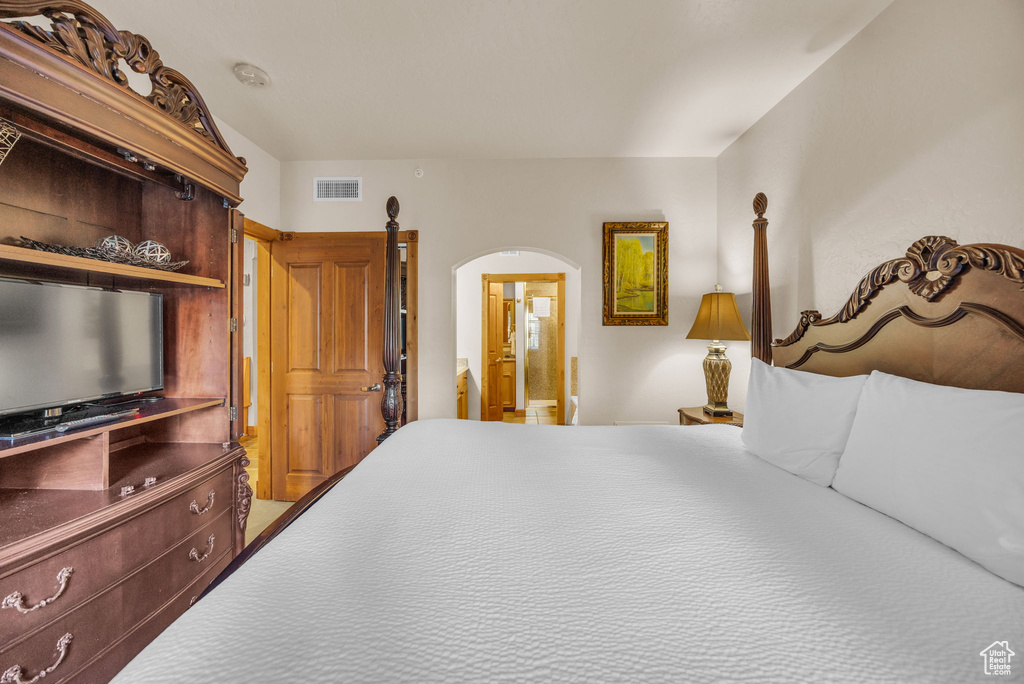 Bedroom featuring arched walkways and ensuite bath