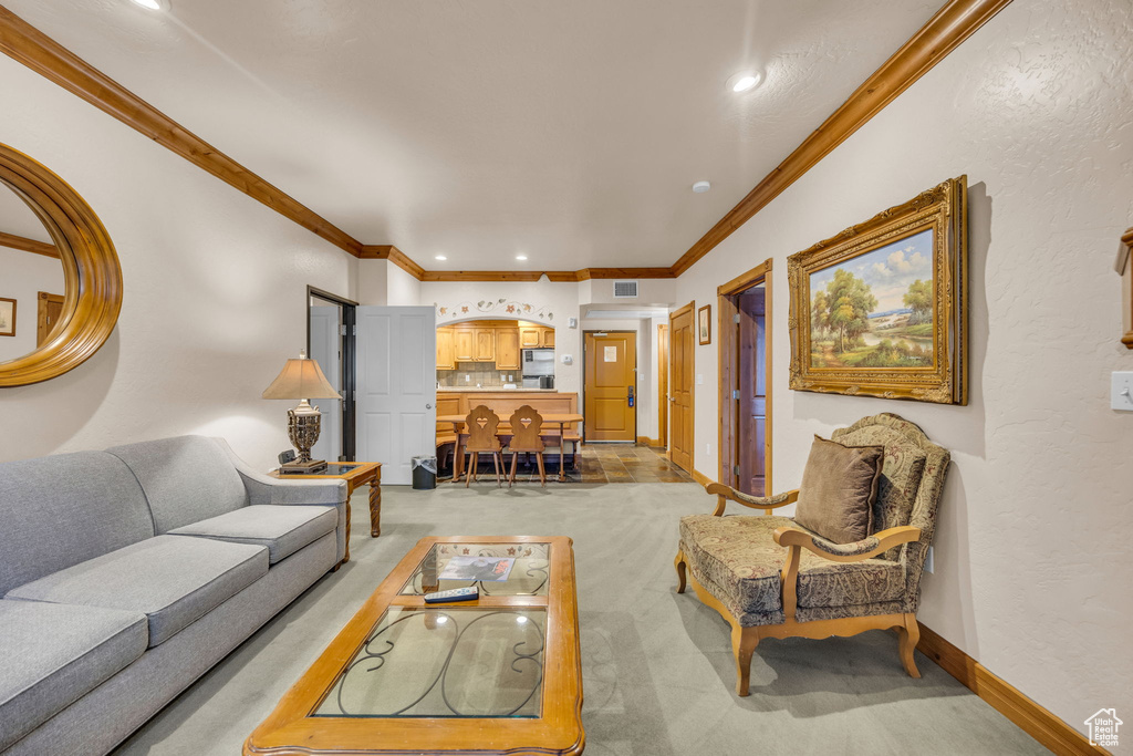 Living room featuring light colored carpet, crown molding, recessed lighting, and baseboards