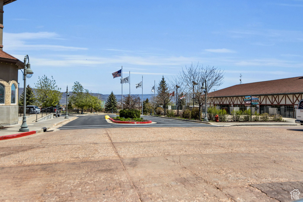 View of asphalt road featuring sidewalks, curbs, and street lights