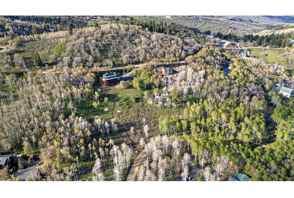 Aerial view of property and surrounding area with a heavily wooded area