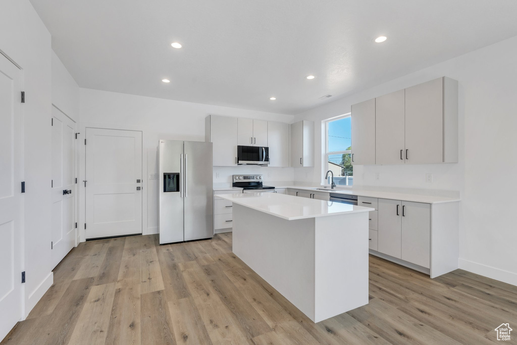 Kitchen featuring stainless steel appliances, a kitchen island, light wood-style flooring, light countertops, and recessed lighting
