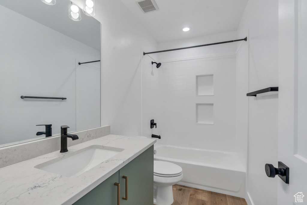 Bathroom with vanity, wood finished floors, toilet, bathtub / shower combination, and recessed lighting